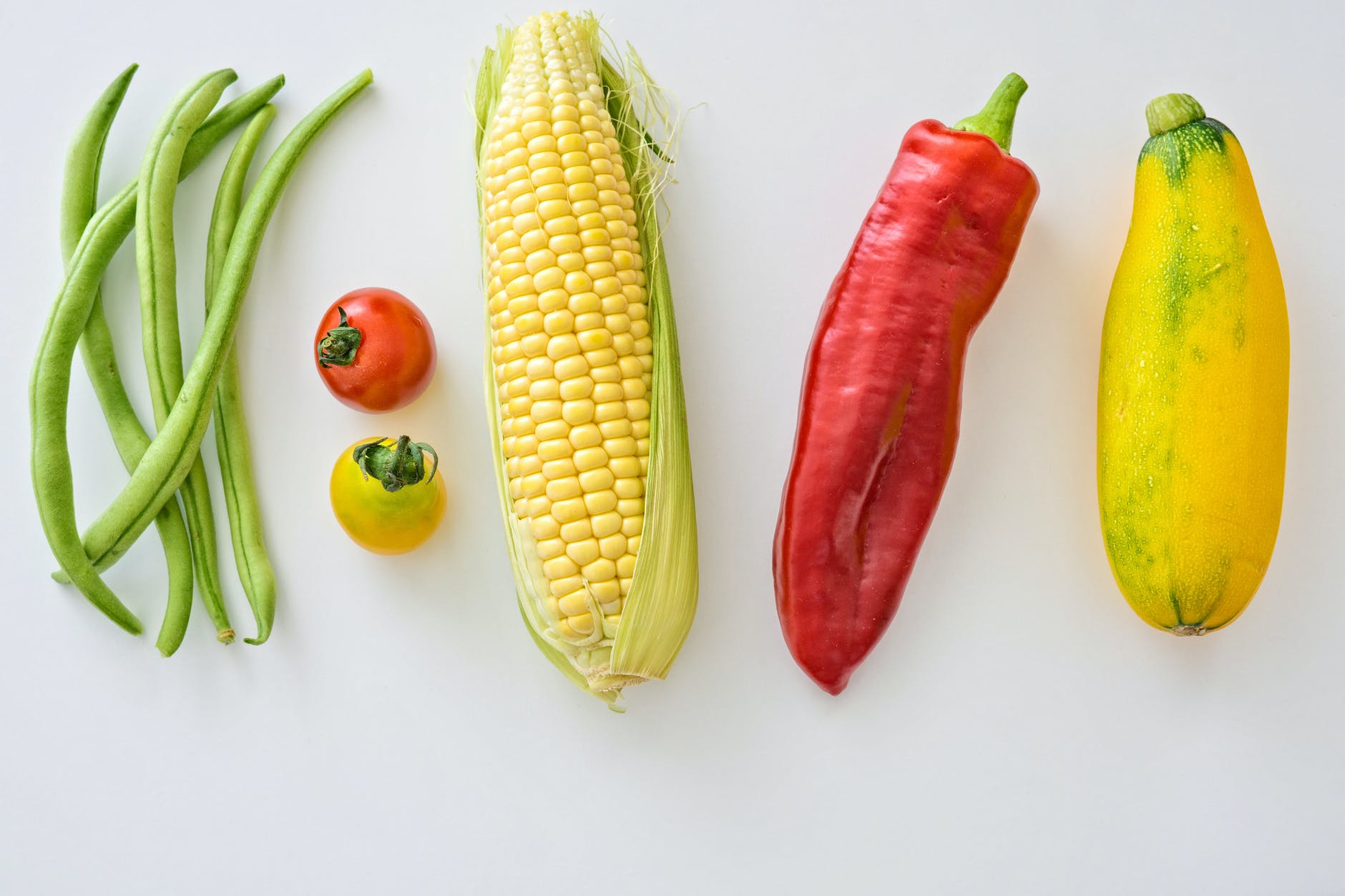Beans, tomatoes, corn, pepper and squash displayed in a row